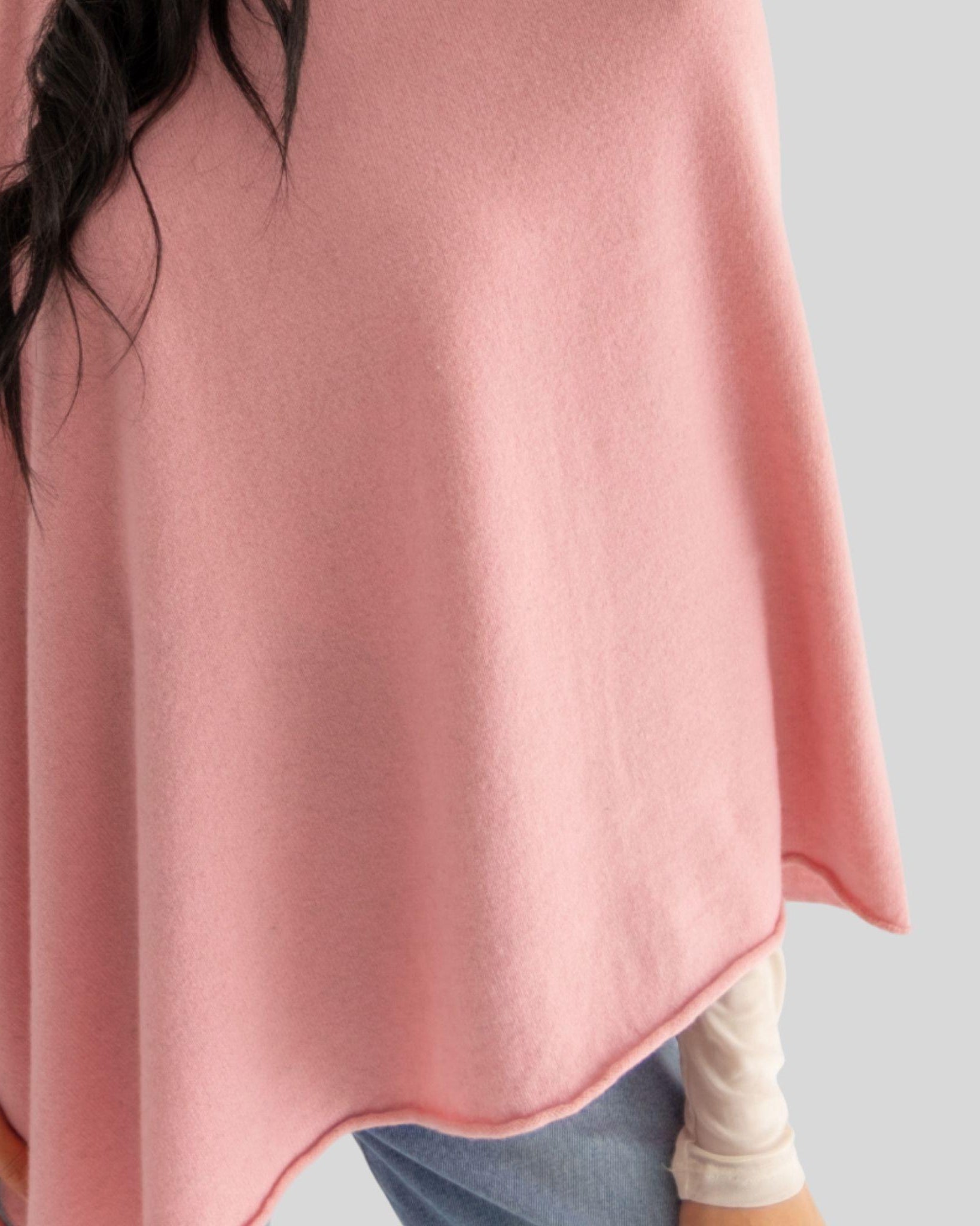 Person wearing a pink poncho on a plain background