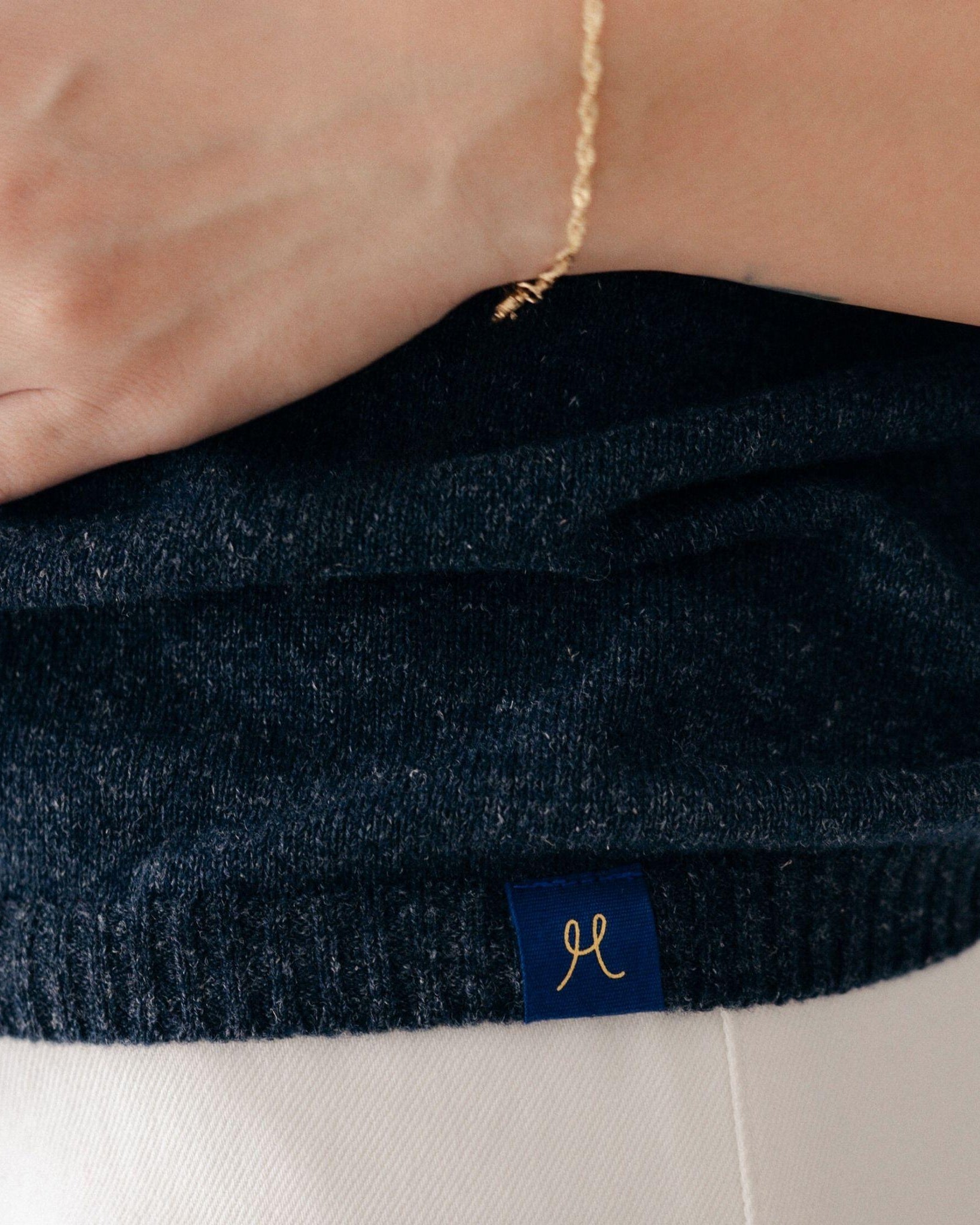 Navy blue sweater with a brand logo on a white background