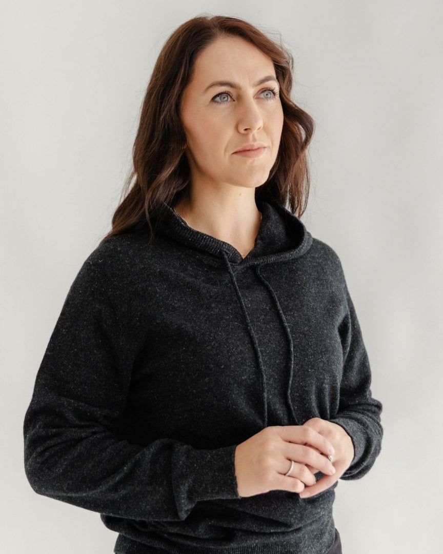 Woman wearing a dark gray hoodie against a plain background