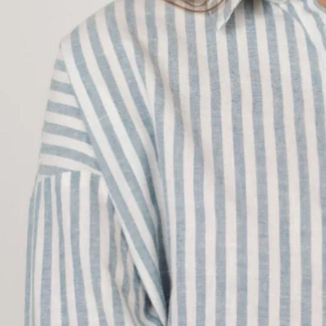 Striped shirt with blue and white vertical stripes on a light gray background