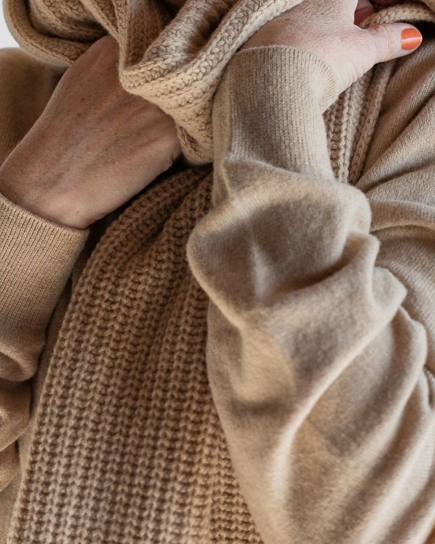 Close-up of a person wearing a beige sweater with a blurred background