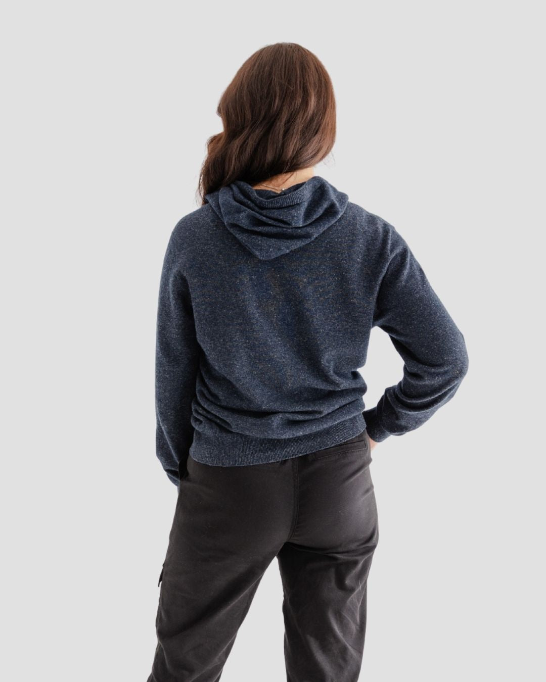 Person wearing a blue hoodie and dark pants on a light gray background