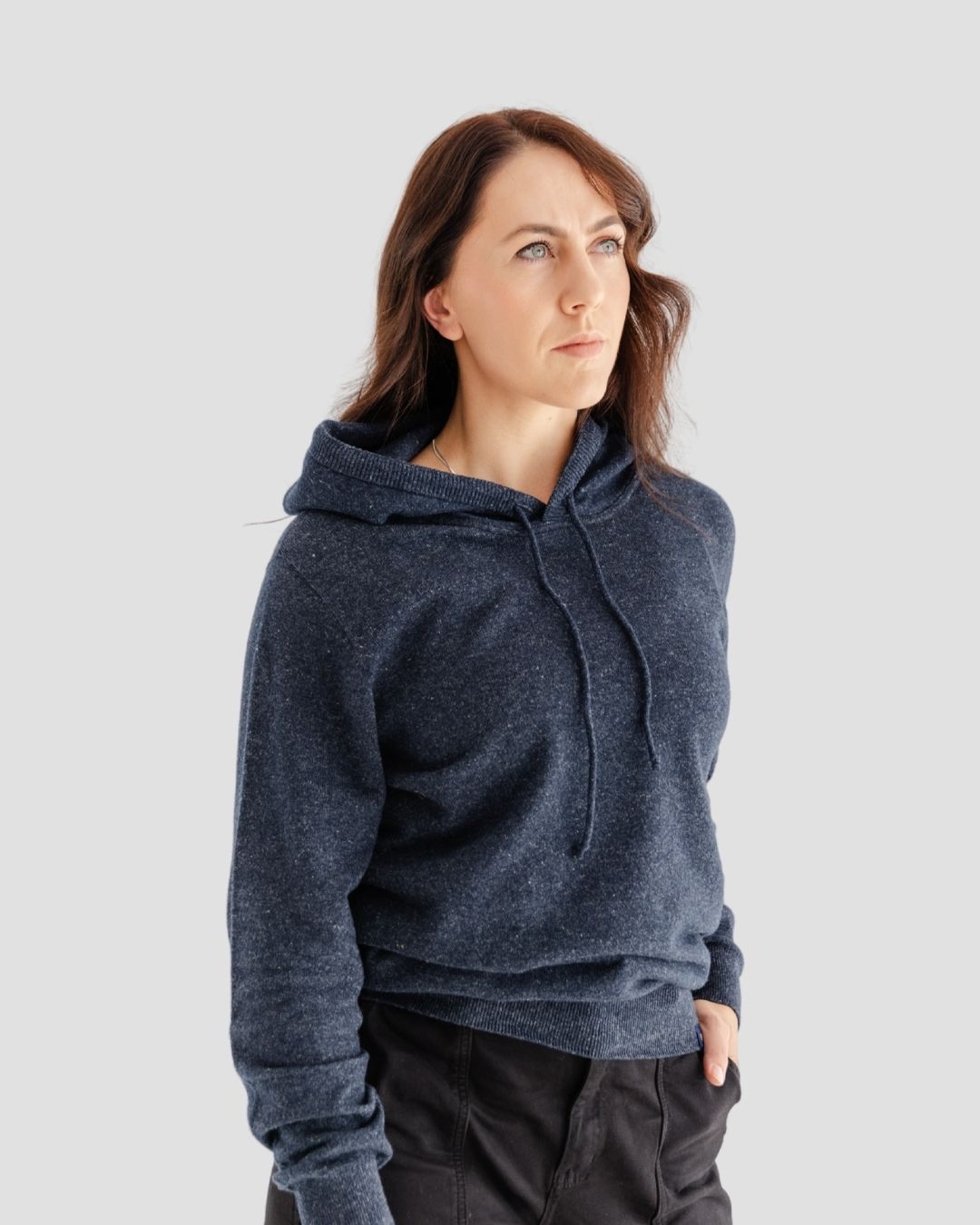 Woman wearing a dark blue hoodie against a light gray background