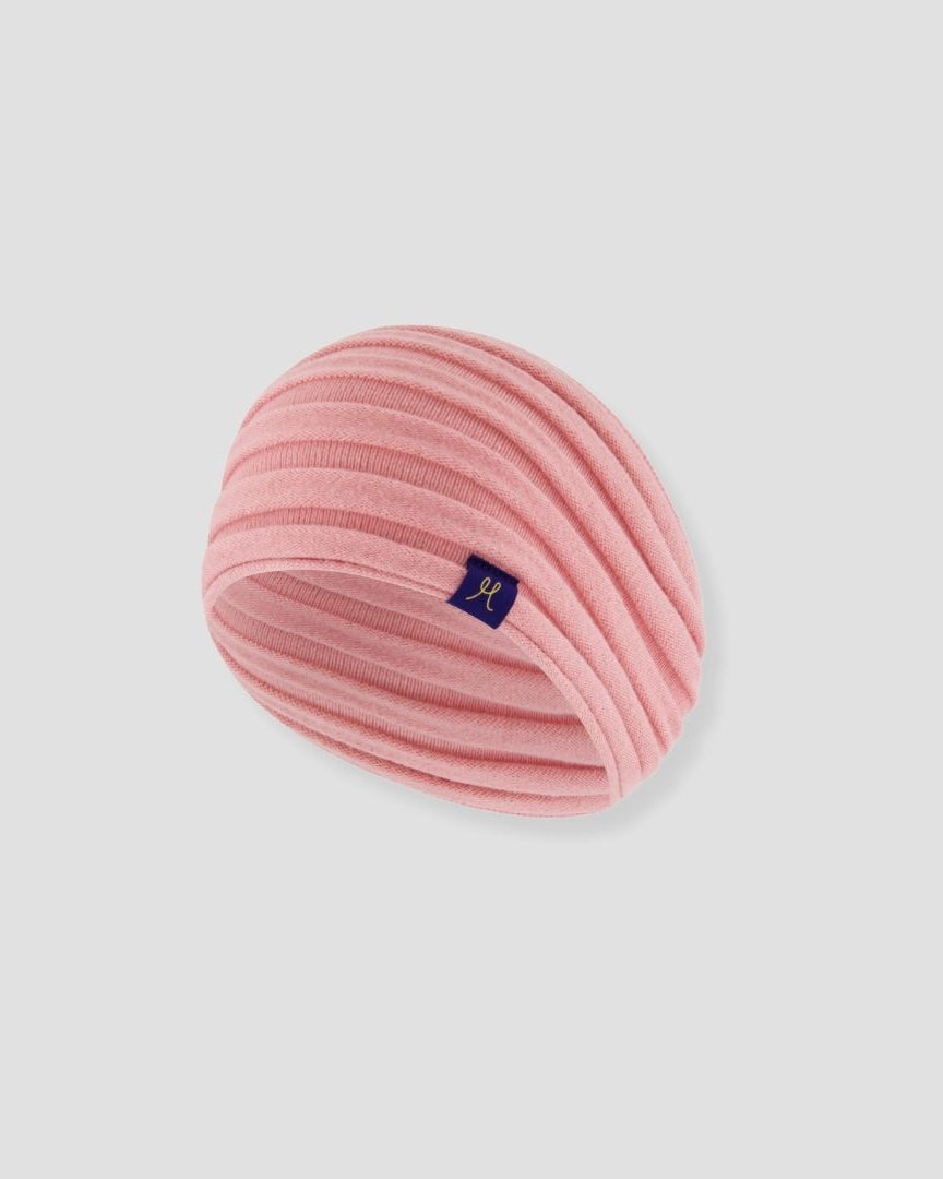 Pink knitted headband with a small logo on a light gray background