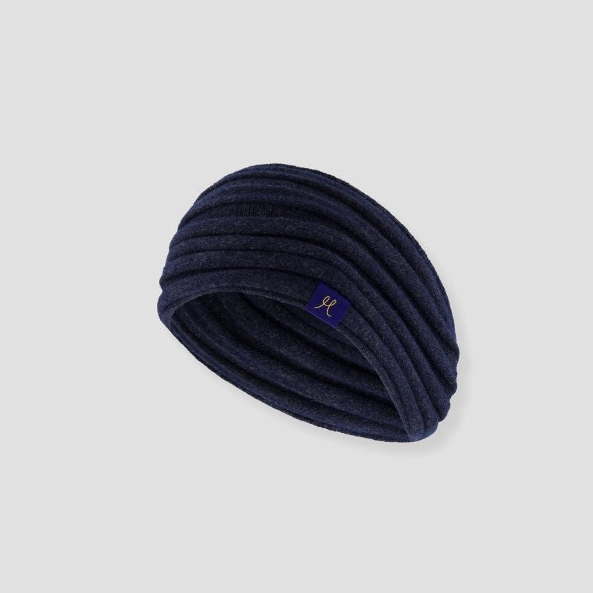 Navy blue knitted headband with a brand logo on a light gray background