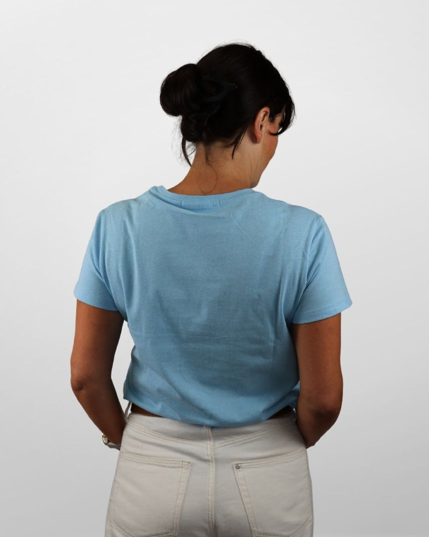 Person wearing a light blue t-shirt and beige pants against a white background