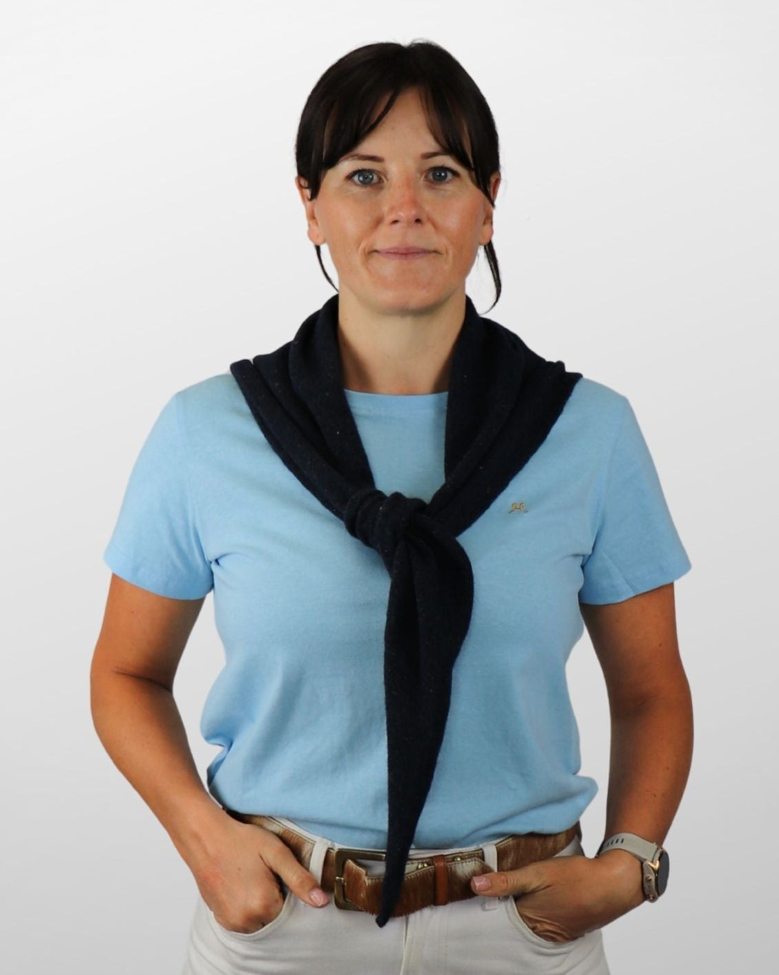 Woman wearing a light blue shirt, black scarf, and beige pants on a white background