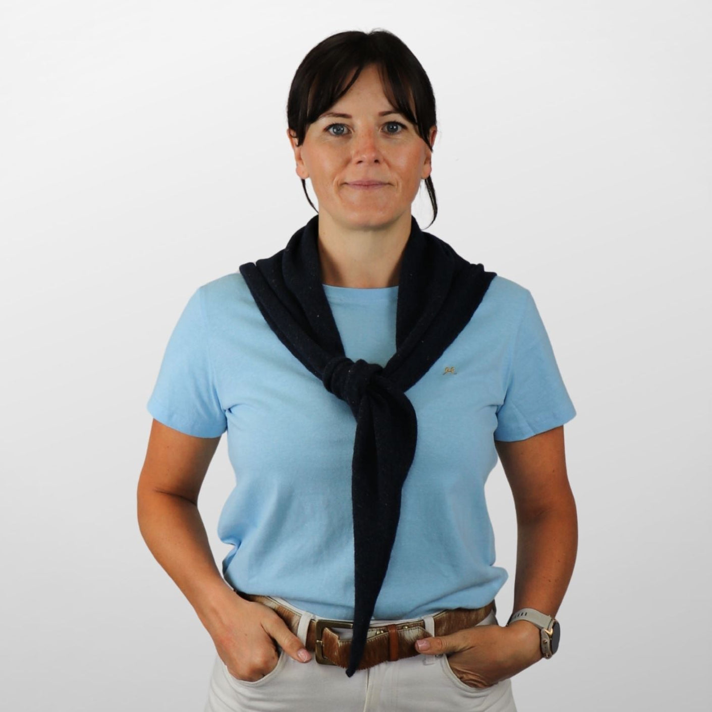 Woman wearing a light blue shirt, black scarf, and beige pants on a white background