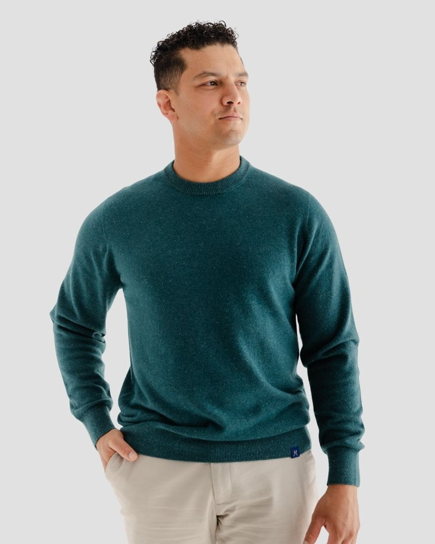 Man wearing a teal sweater against a plain background