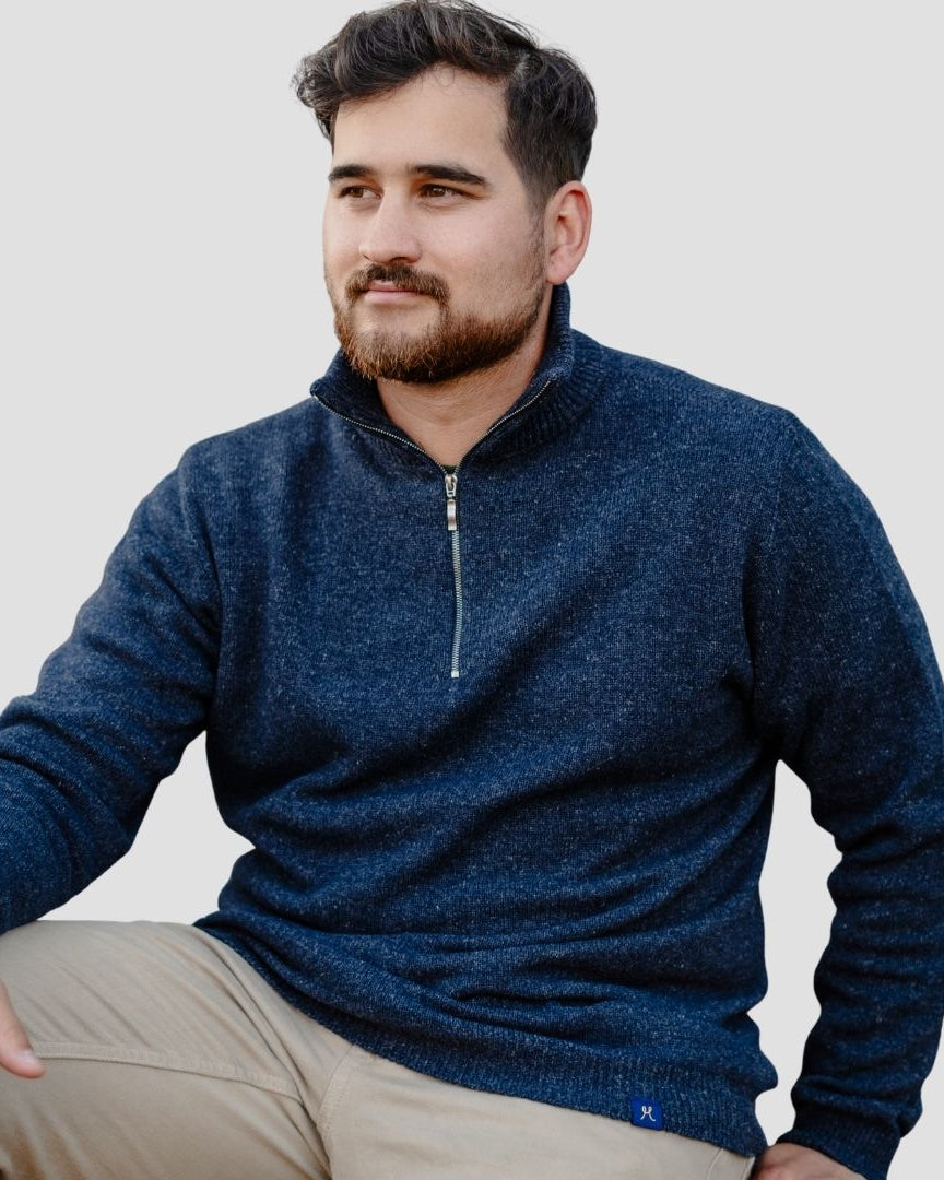Man wearing a blue sweater with a zipper on a plain background