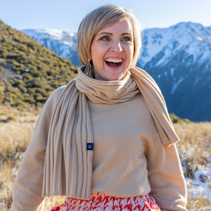 Blonde lady looks happy in beige matching scarf and crew sweater.