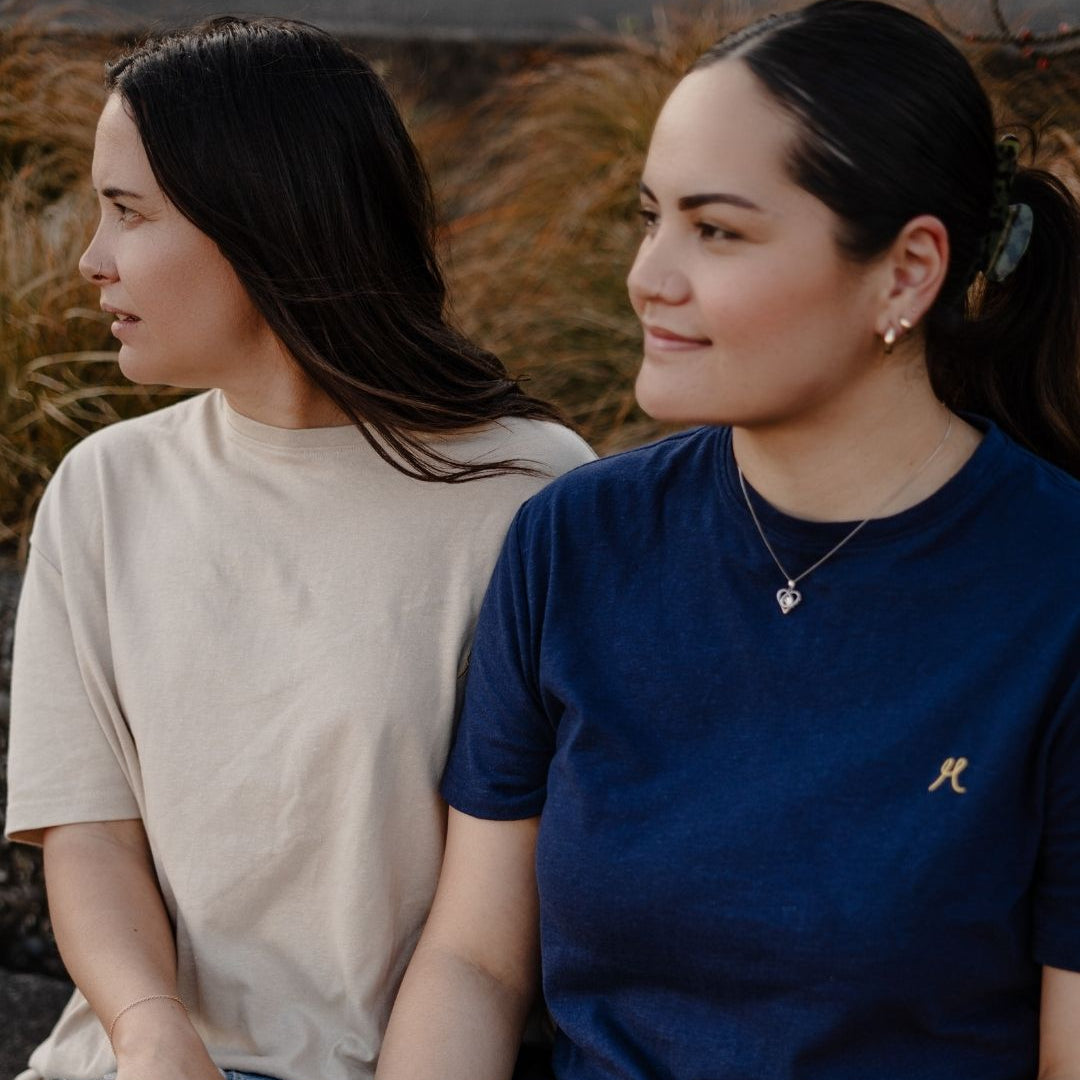 Two women sitting side by side outdoors with a natural background