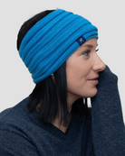 A person wearing a blue rib-knit headband with a label visible on the side.