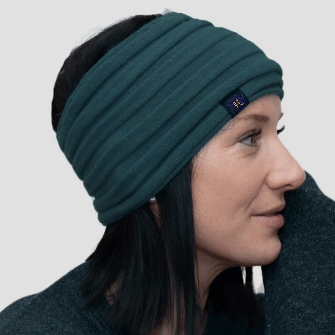 Woman wearing a teal headband with a brand logo on a light gray background