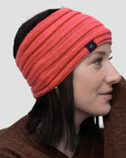 Woman wearing a coral headband with a brand logo on a plain background
