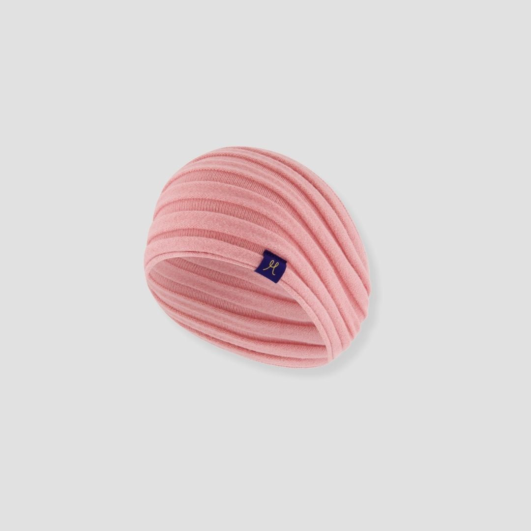 Pink knitted headband with a small logo on a light gray background