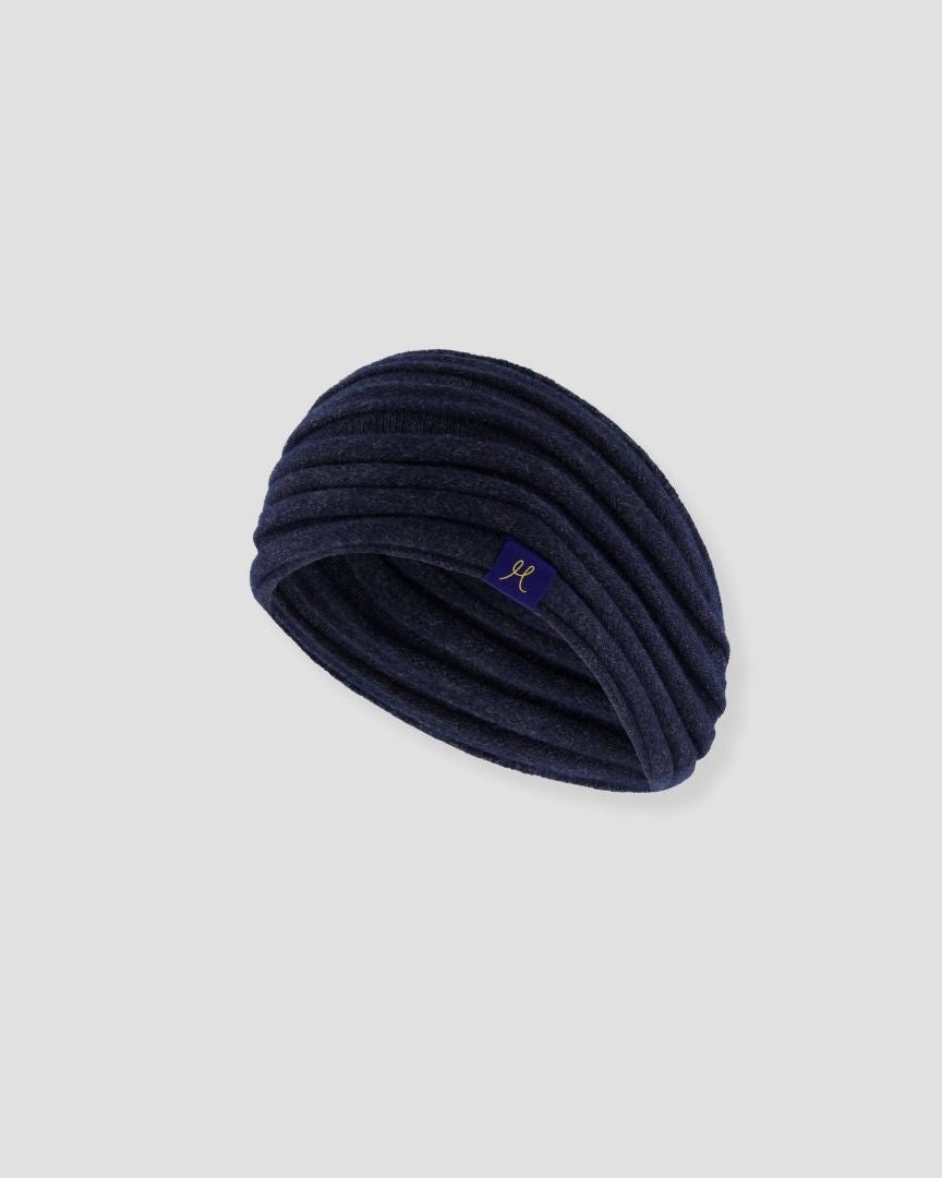 Navy blue knitted headband with a brand logo on a light gray background