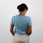Person wearing a light blue t-shirt and beige pants against a white background