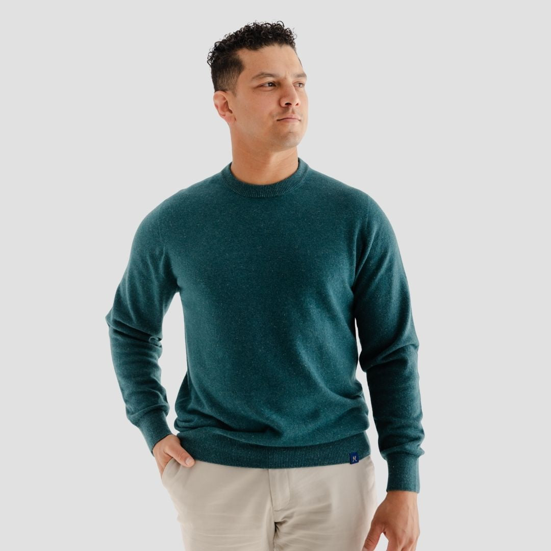 Man wearing a teal sweater against a plain background