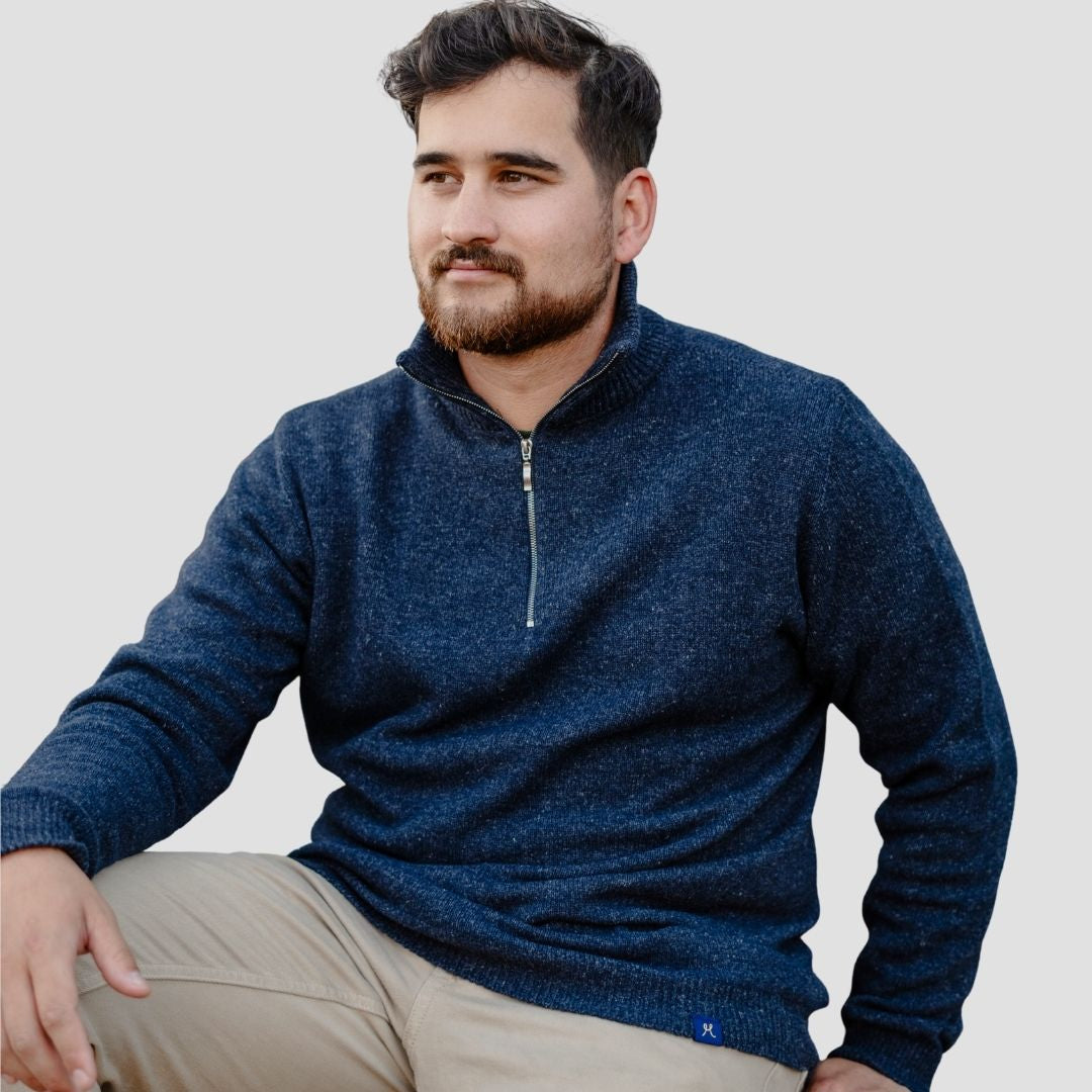 Man wearing a blue sweater with a zipper on a plain background