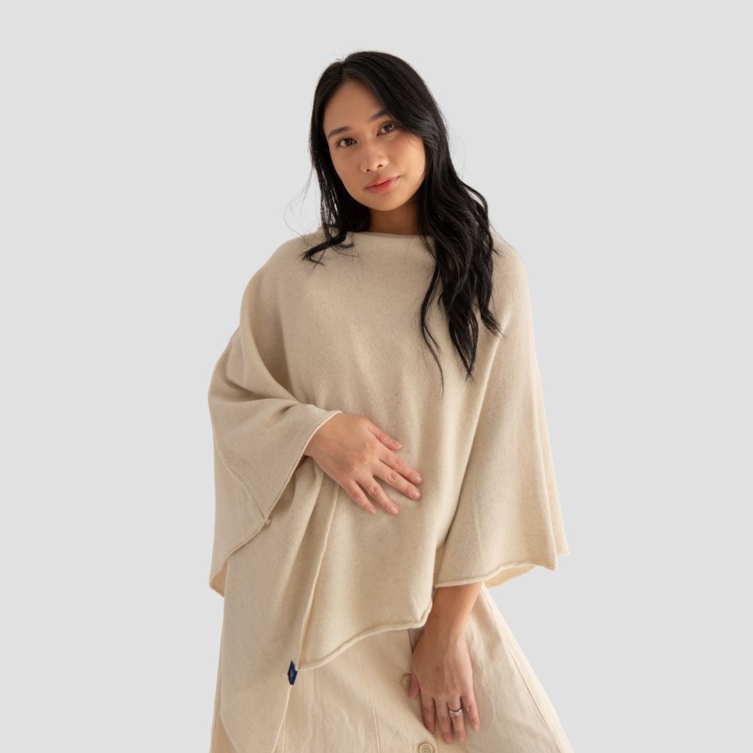Woman wearing a beige poncho against a plain background