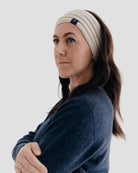 Woman wearing a white headband with a logo on a plain background