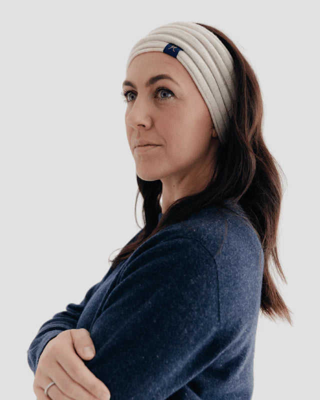 Woman wearing a white headband with a logo on a plain background