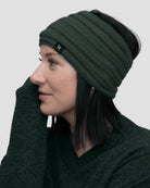 Woman wearing a green beanie and scarf on a plain background