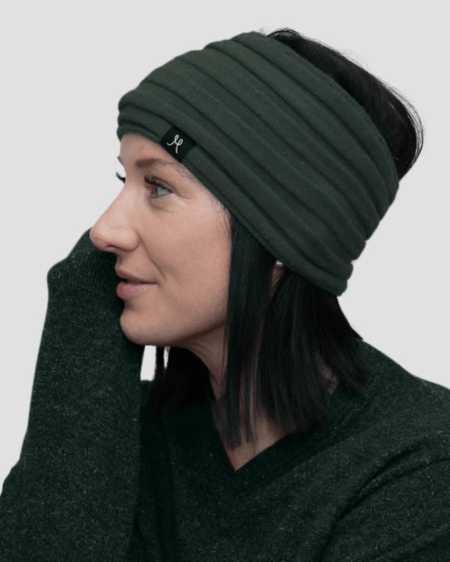 Woman wearing a green beanie and scarf on a plain background