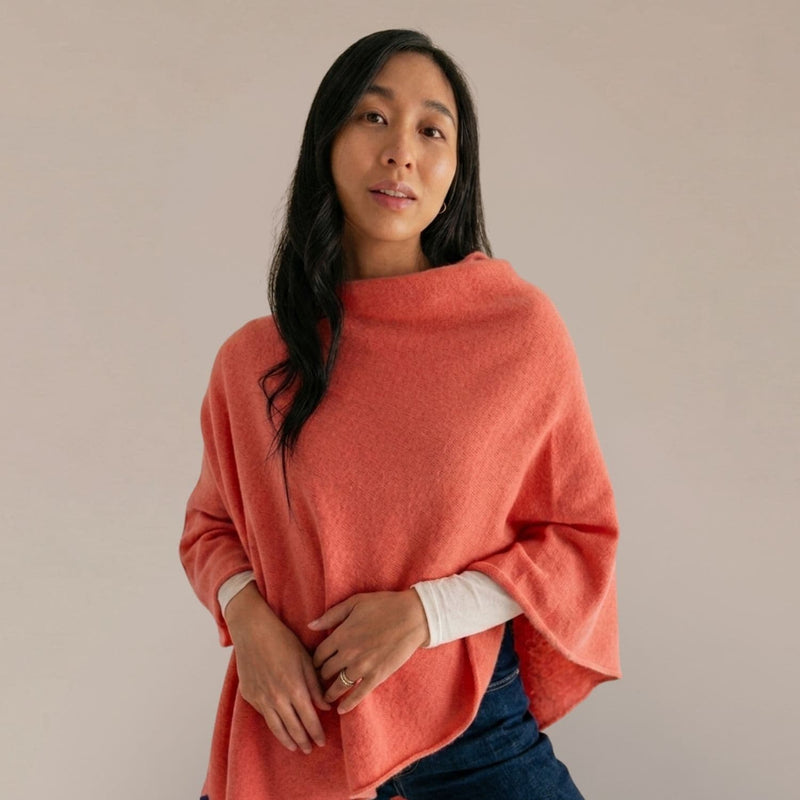 Woman wearing a coral poncho against a beige background