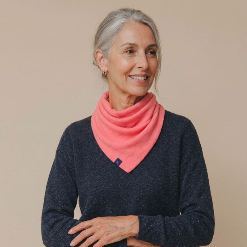Woman wearing a pink scarf and dark blue sweater against a beige background