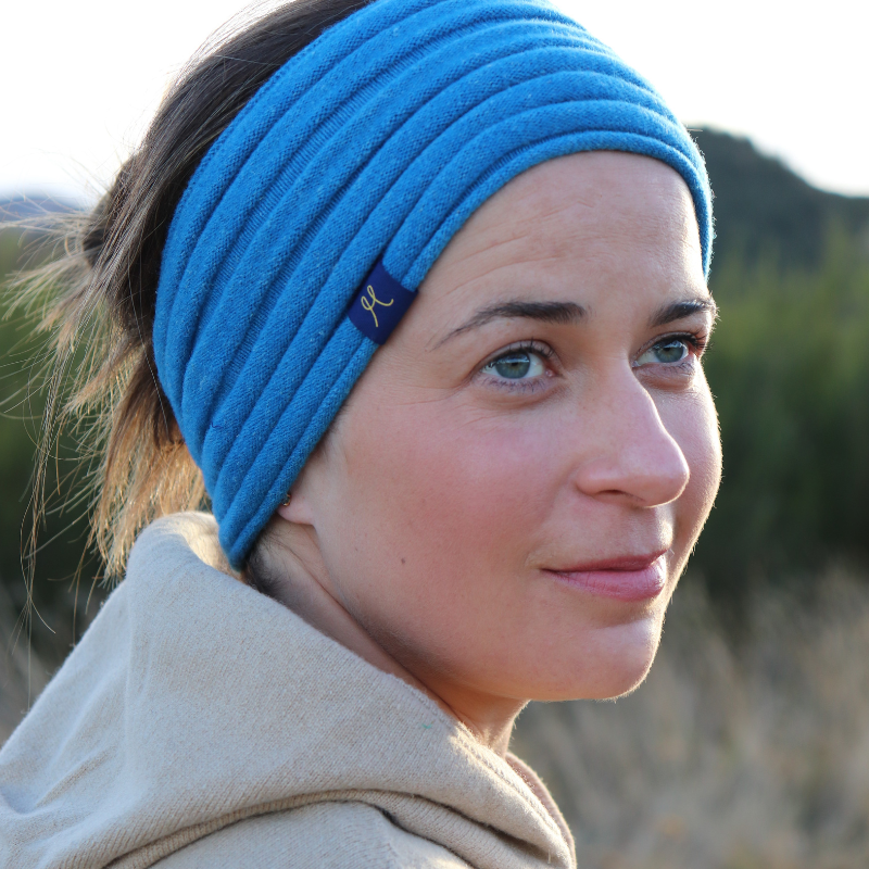 Young lady wearing beige hooded sweater and a aqua blue headband gathered style with her hair up.