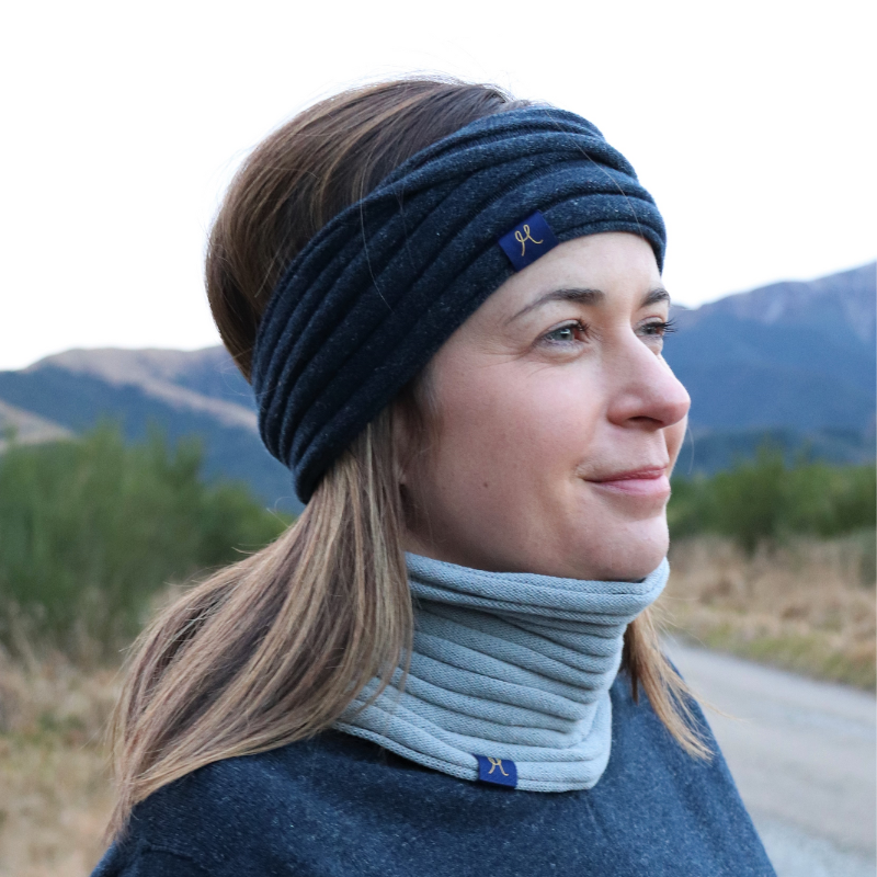 Lady enjoying the outdoors, mountain views and tramping. She is wearing a dark blue headband and grey neckwarmer buff from Hemprino.