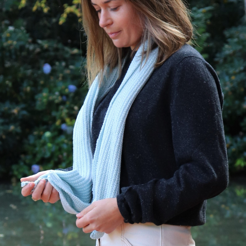 Thirty year old women wearing a beautiful light blue scarf and charcoal jersey from brand Hemprino. Made from Hemp and merino wool.