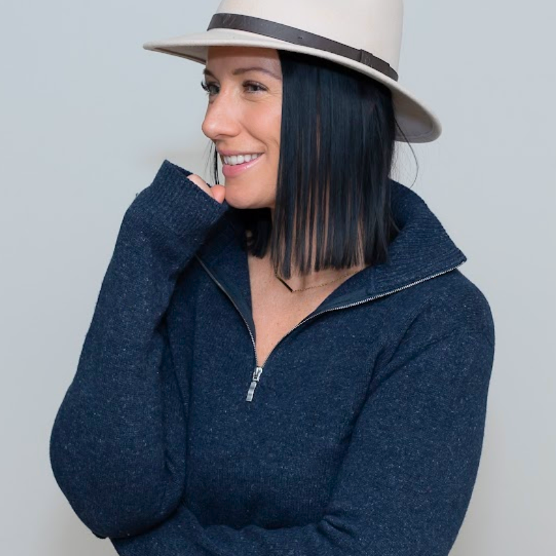 Pretty brunette lady wearing navy blue zip up sweater and hat