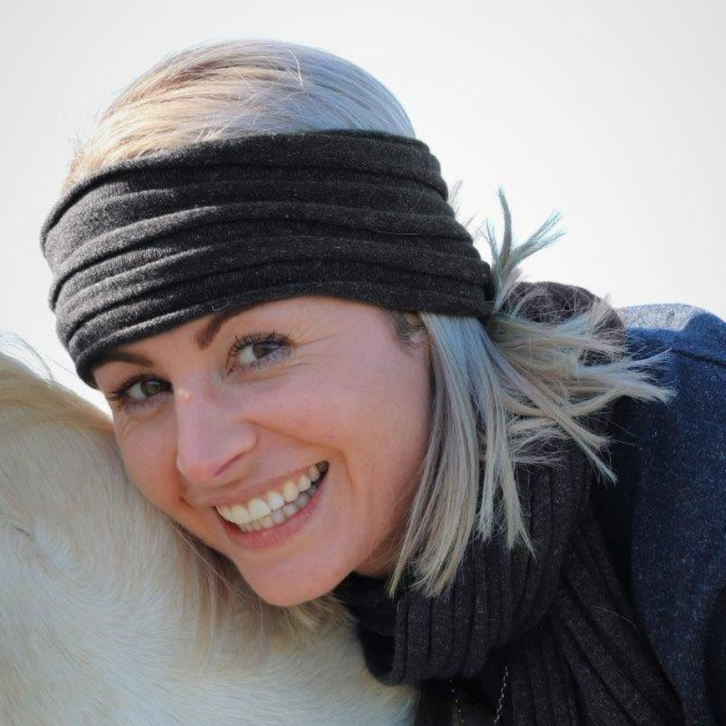 Lady wearing hemprino rib knit headband in charcoal dark grey while riding a horse. 